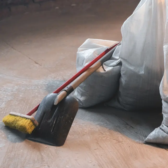 Balai et pelle reposant contre des sacs de débris dans une zone de chantier, dénotant le service complet de nettoyage de fin de chantier d'ISL Nettoyage.
