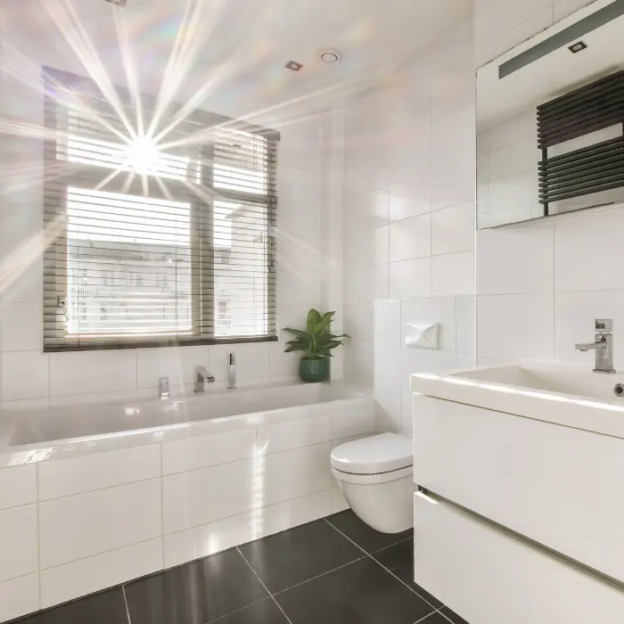 Salle de bain immaculée baignée de lumière, avec des carreaux blancs brillants et une plante verte, reflétant la qualité du service de nettoyage occasionnel d'ISL Nettoyage.