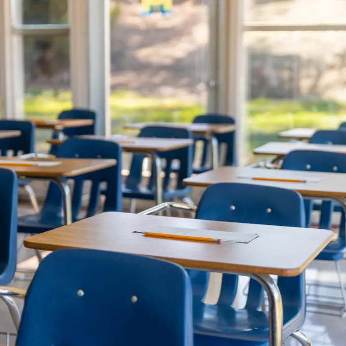 Salle de classe lumineuse avec des bureaux bien rangés et des chaises bleues, indiquant le niveau de propreté quotidien maintenu par ISL Nettoyage.