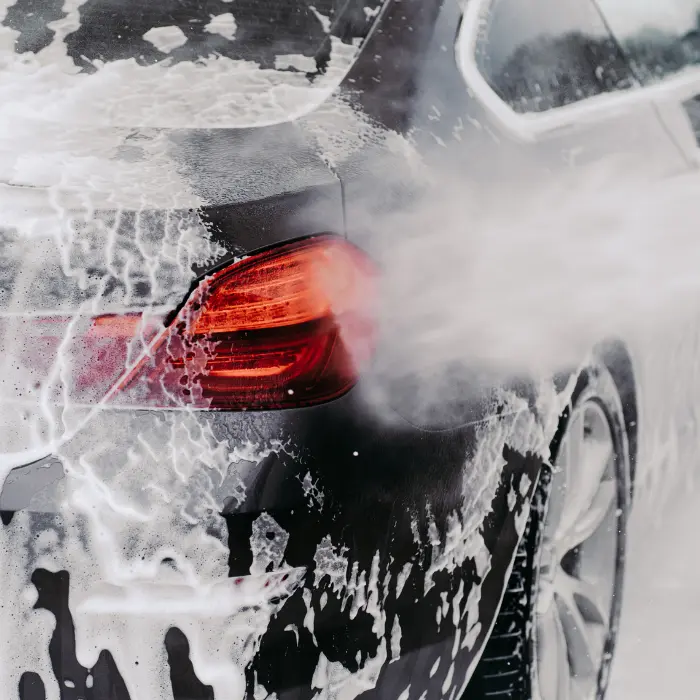 Nettoyage à haute pression de la carrosserie d'une voiture, reflétant la brillance et la propreté offertes par nos services de nettoyage de véhicules.