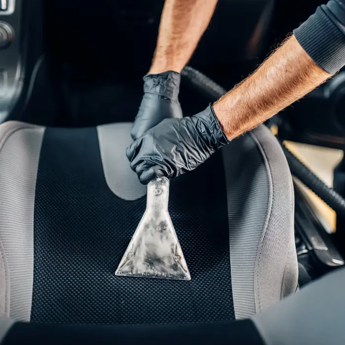 Nettoyage professionnel d'un siège de voiture avec un extracteur, garantissant un intérieur de véhicule impeccable et hygiénique.