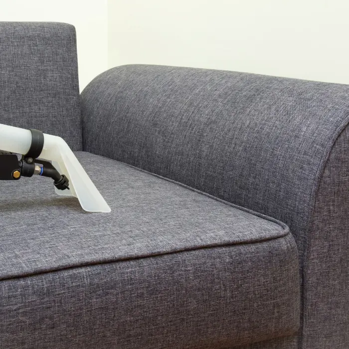 Nettoyage professionnel d'un canapé en tissu avec un équipement de nettoyage à vapeur, démontrant les services de nettoyage de mobilier d'ISL Nettoyage