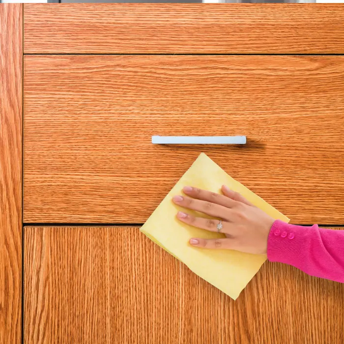 Nettoyage délicat d'un tiroir en chêne avec un chiffon doux, reflétant la précision et le soin des services de nettoyage de mobilier d'ISL Nettoyage